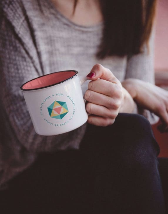 Mockup of a submark on a metal mug being held by a woman whose face you do not see.